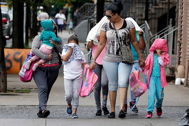 Migrant children shield their faces while leaving the Cayuga Center in East Harlem
